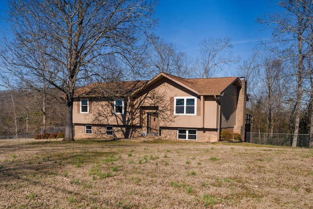 view of front of house with brick siding, a chimney, a front yard, and fence