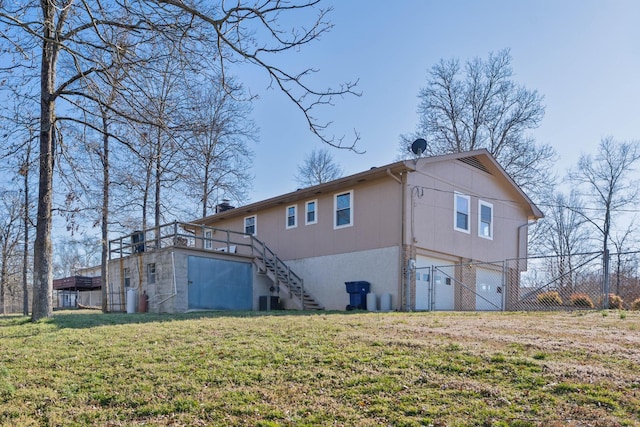 rear view of property with a garage, dirt driveway, a lawn, stairway, and central air condition unit