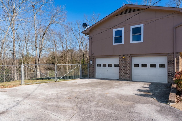 view of property exterior with a gate, fence, aphalt driveway, and brick siding