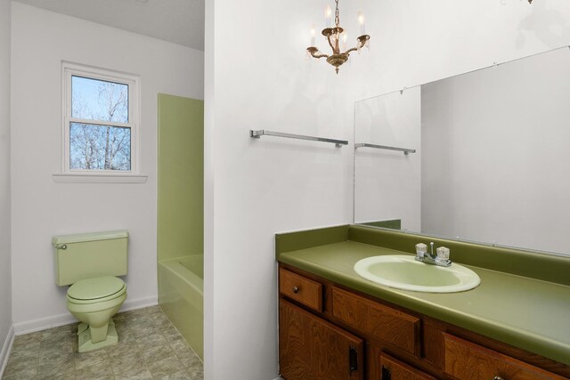 bathroom featuring a bathtub, a notable chandelier, toilet, vanity, and baseboards