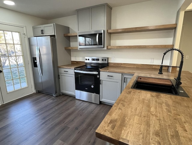 kitchen with dark wood-style flooring, open shelves, wooden counters, appliances with stainless steel finishes, and a sink