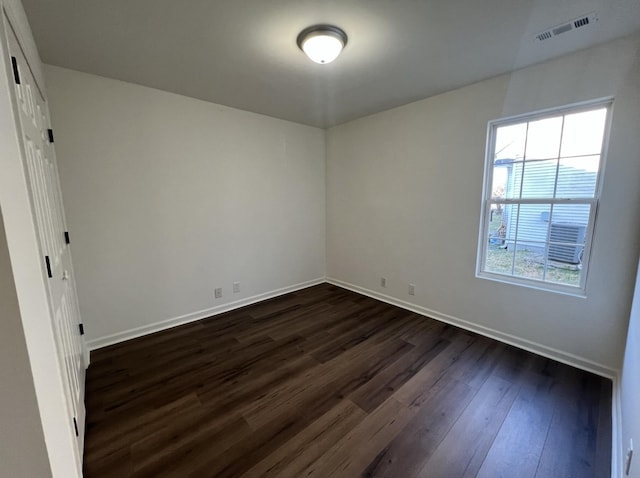 unfurnished bedroom with dark wood-style floors, visible vents, and baseboards