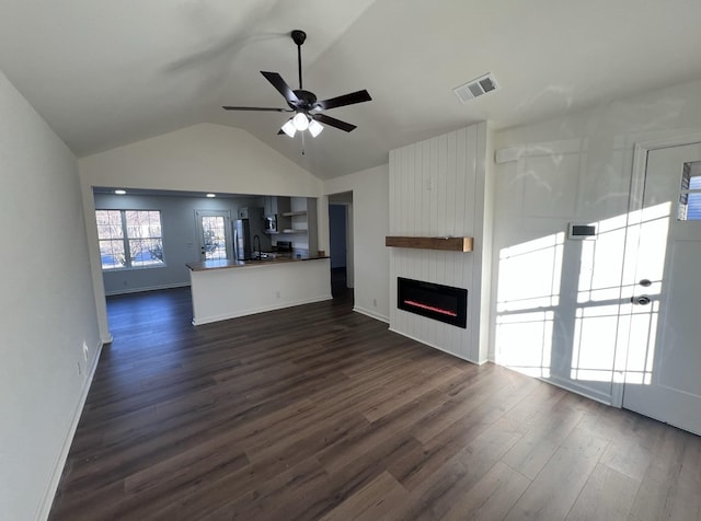 unfurnished living room with dark wood-style flooring, a fireplace, lofted ceiling, visible vents, and a ceiling fan