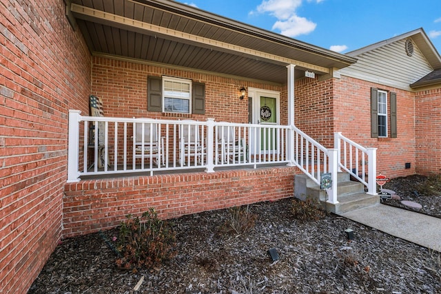 doorway to property with a porch and brick siding