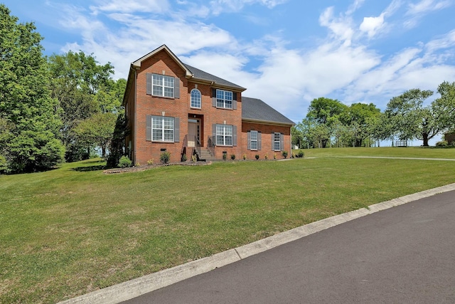 colonial inspired home featuring brick siding and a front lawn