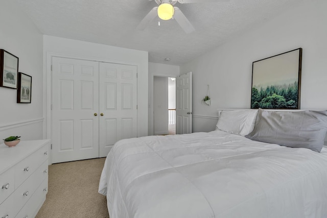 bedroom featuring ceiling fan, a textured ceiling, a closet, and light colored carpet