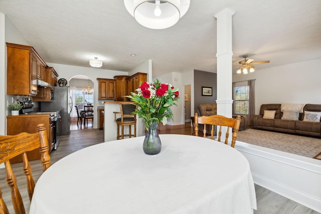 dining room with arched walkways, dark wood-style flooring, ceiling fan, and ornate columns