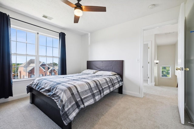 bedroom featuring baseboards, visible vents, ceiling fan, and light colored carpet