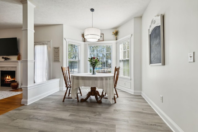 dining space with a textured ceiling, a premium fireplace, wood finished floors, and baseboards