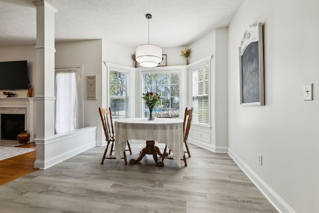 dining space featuring a premium fireplace, a textured ceiling, baseboards, and wood finished floors