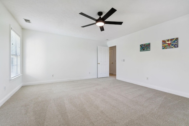 carpeted spare room featuring ceiling fan, visible vents, and baseboards