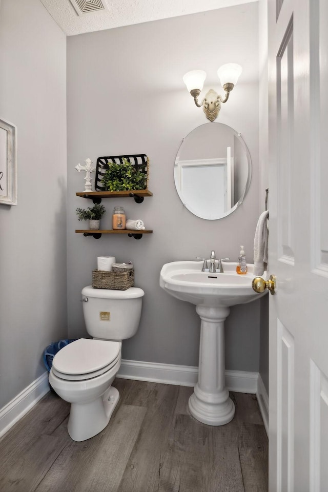 bathroom with wood finished floors, toilet, and baseboards