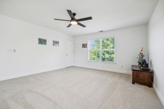 unfurnished room with carpet, visible vents, baseboards, and a ceiling fan