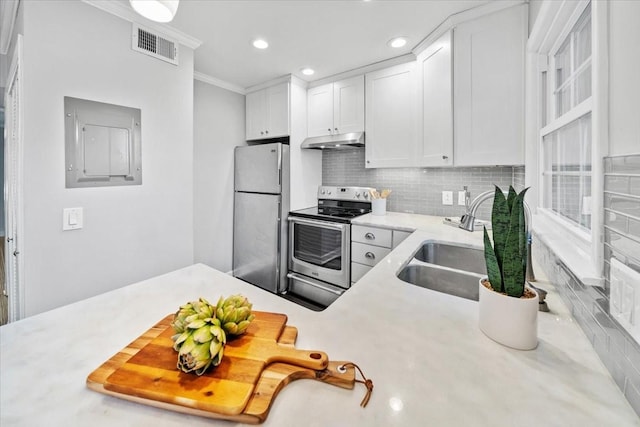 kitchen with appliances with stainless steel finishes, light countertops, a sink, and under cabinet range hood