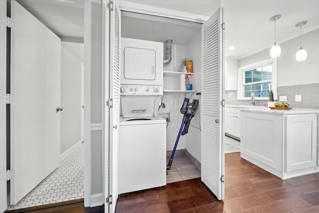 laundry area featuring laundry area, stacked washer / dryer, ornamental molding, dark wood-style flooring, and a sink