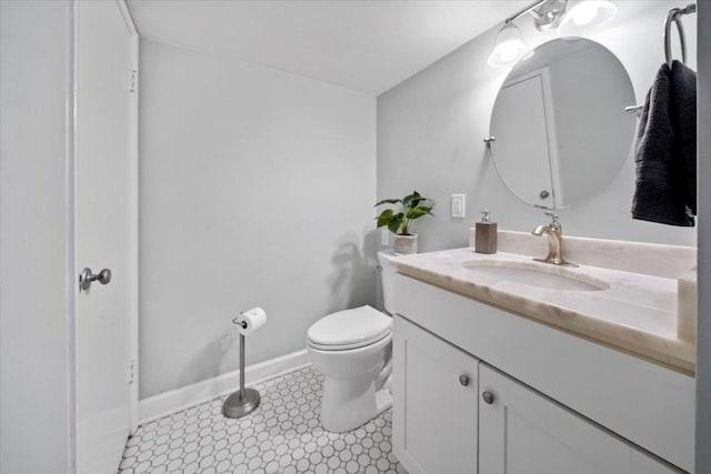 bathroom featuring toilet, vanity, and baseboards