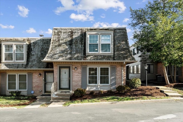 view of front of home featuring mansard roof and brick siding