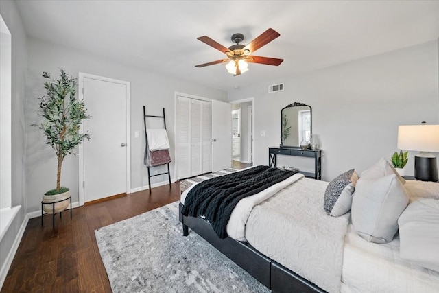 bedroom with wood finished floors, a ceiling fan, baseboards, visible vents, and multiple closets