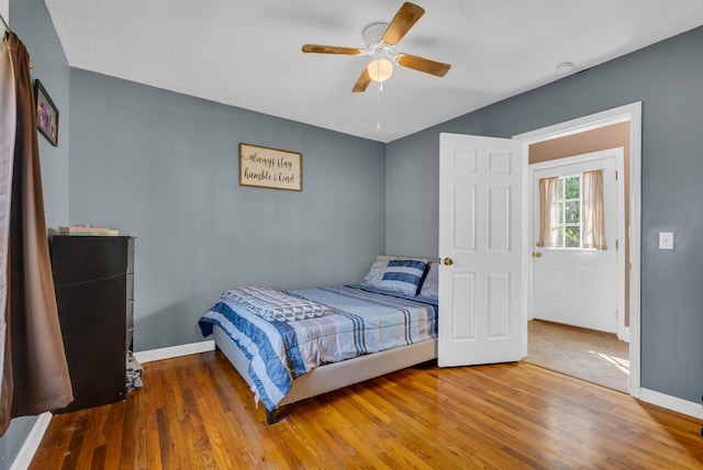 bedroom featuring ceiling fan, baseboards, and wood finished floors