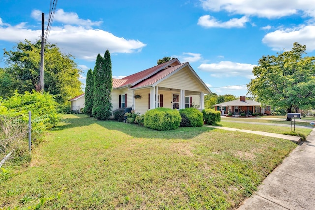 bungalow-style home with metal roof, a porch, and a front lawn