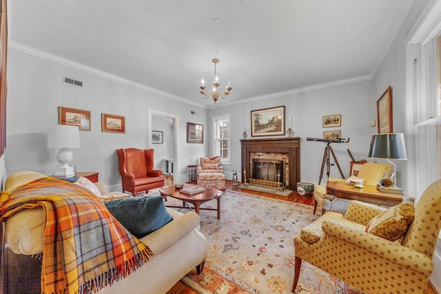 living room featuring wood finished floors, visible vents, an inviting chandelier, a glass covered fireplace, and crown molding