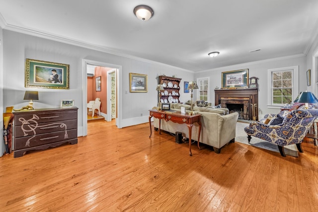 living room with baseboards, crown molding, a stone fireplace, and hardwood / wood-style floors