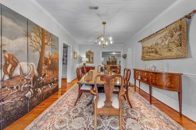 dining room with crown molding, wood finished floors, visible vents, and a notable chandelier