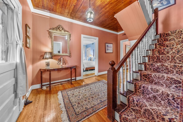 foyer featuring hardwood / wood-style floors, stairway, wooden ceiling, and crown molding