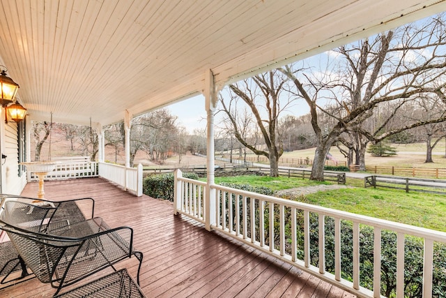 wooden terrace featuring covered porch and fence