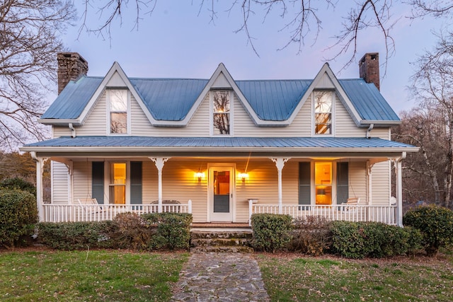 view of front of property featuring covered porch, a chimney, and metal roof