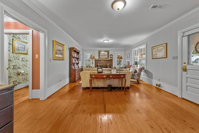 living area with ornamental molding, light wood-style floors, a healthy amount of sunlight, and a fireplace