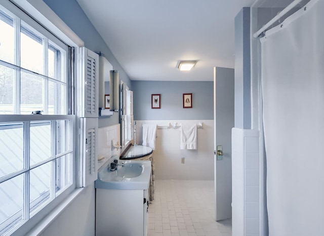 full bath with wainscoting, curtained shower, tile walls, and vanity