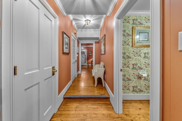 corridor featuring baseboards, crown molding, light wood finished floors, and wallpapered walls