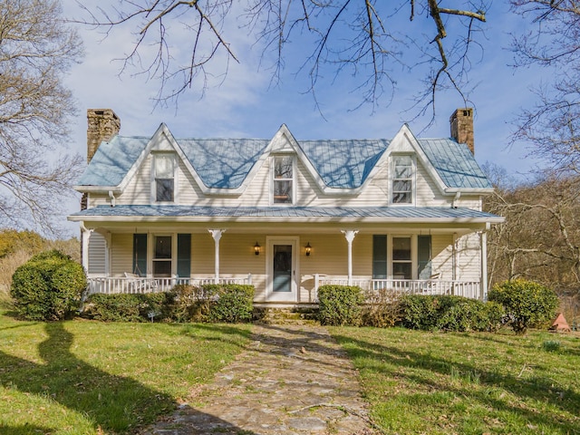 view of front of home with covered porch, a chimney, and a front lawn