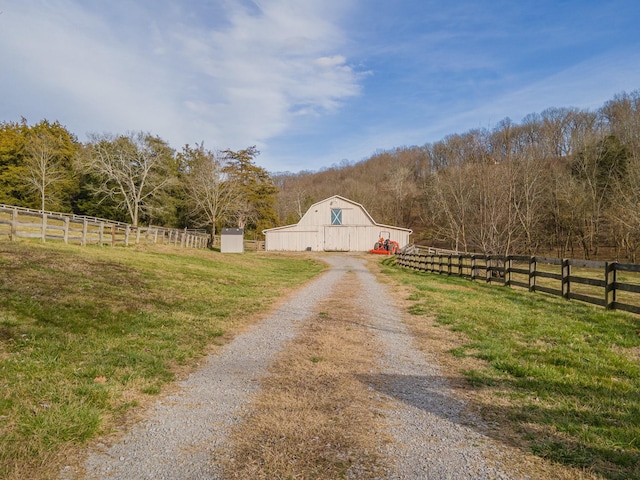 view of street with a barn, driveway, and a rural view