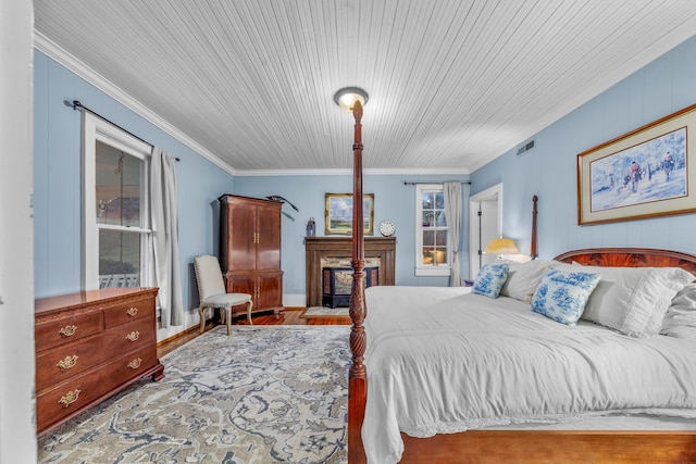 bedroom featuring wooden ceiling, a fireplace, wood finished floors, visible vents, and ornamental molding