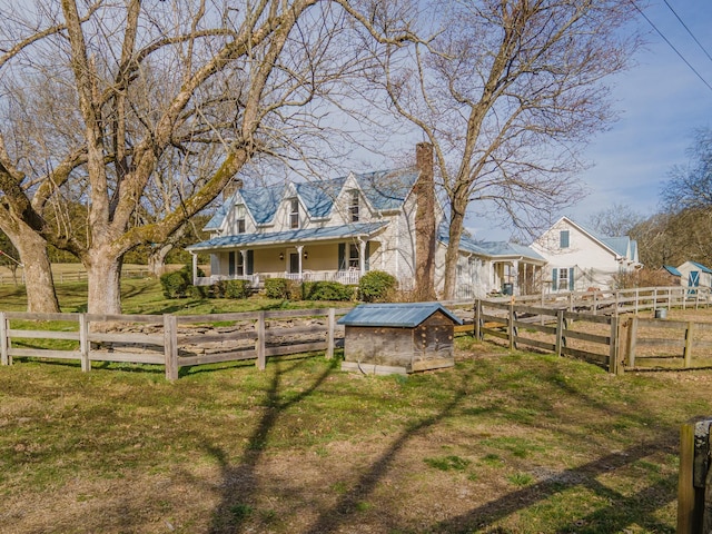 view of front of property with a fenced front yard, a chimney, metal roof, an outdoor structure, and a front lawn