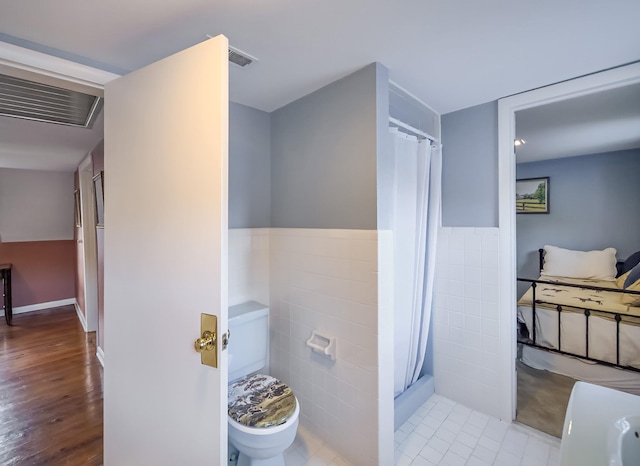 bathroom featuring visible vents, toilet, a wainscoted wall, curtained shower, and tile walls