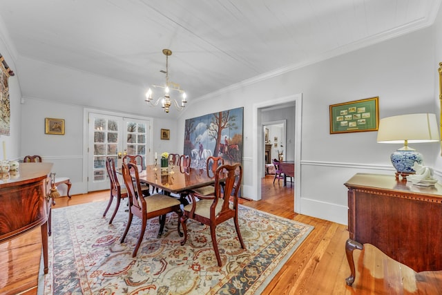 dining room with vaulted ceiling, crown molding, french doors, light wood-type flooring, and a chandelier