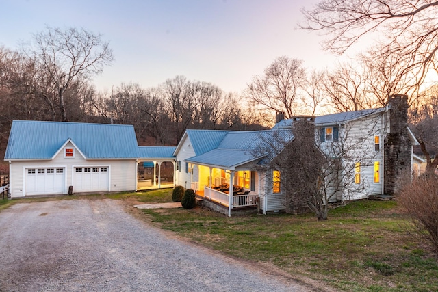 view of front of property featuring metal roof, driveway, a chimney, and a lawn