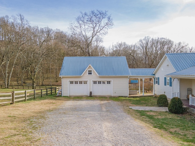 view of front of property featuring a carport, metal roof, fence, a garage, and driveway