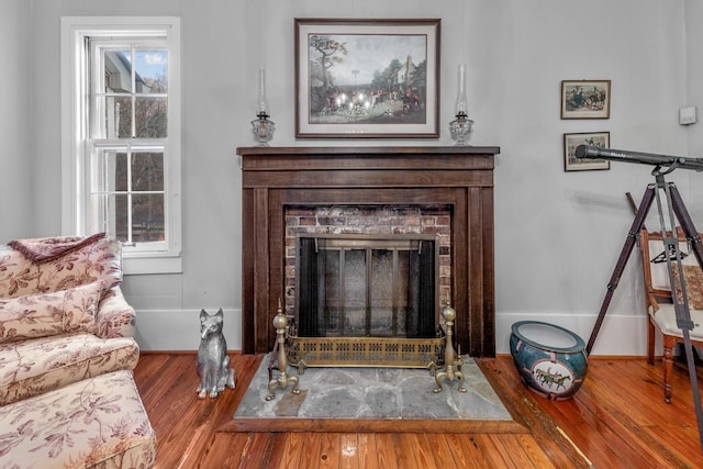 living room with a fireplace, baseboards, and wood finished floors