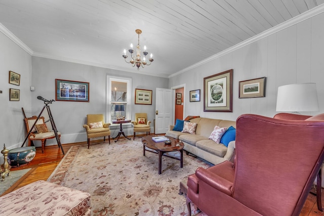 living area with baseboards, ornamental molding, wood finished floors, and a notable chandelier