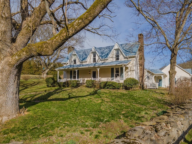 view of front of house with covered porch, a chimney, and a front yard