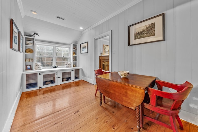 dining area with visible vents, baseboards, vaulted ceiling, hardwood / wood-style floors, and crown molding