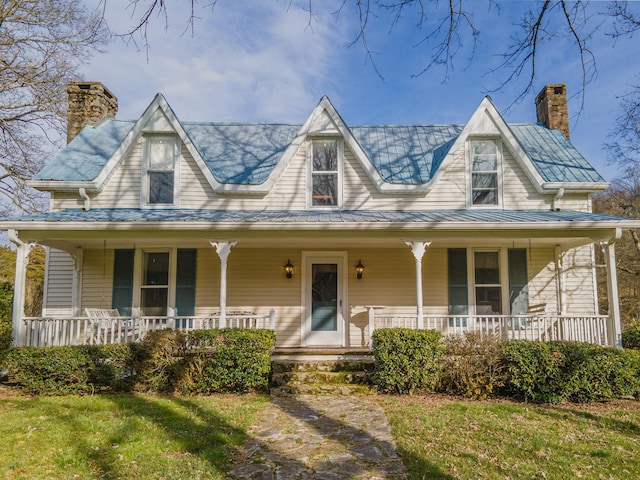 farmhouse featuring covered porch, metal roof, and a chimney