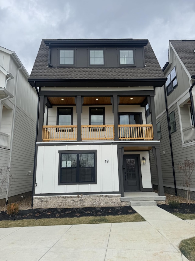 view of front of house with roof with shingles, board and batten siding, and a balcony