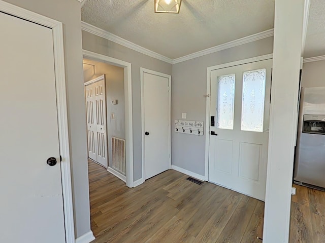 entrance foyer with visible vents, crown molding, a textured ceiling, and wood finished floors