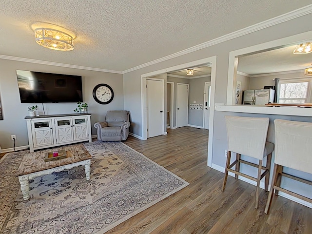 living area with crown molding, a textured ceiling, baseboards, and wood finished floors