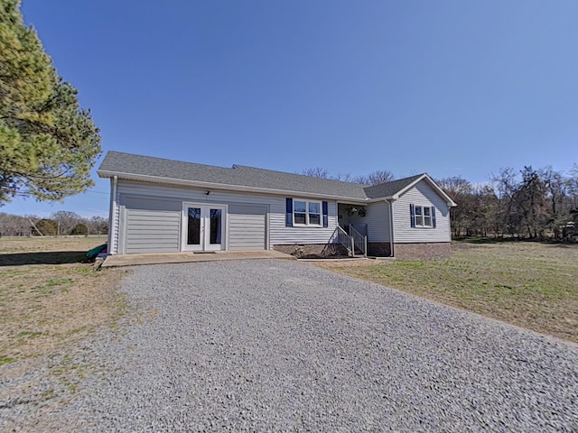 ranch-style house with a front yard, french doors, an attached garage, and gravel driveway